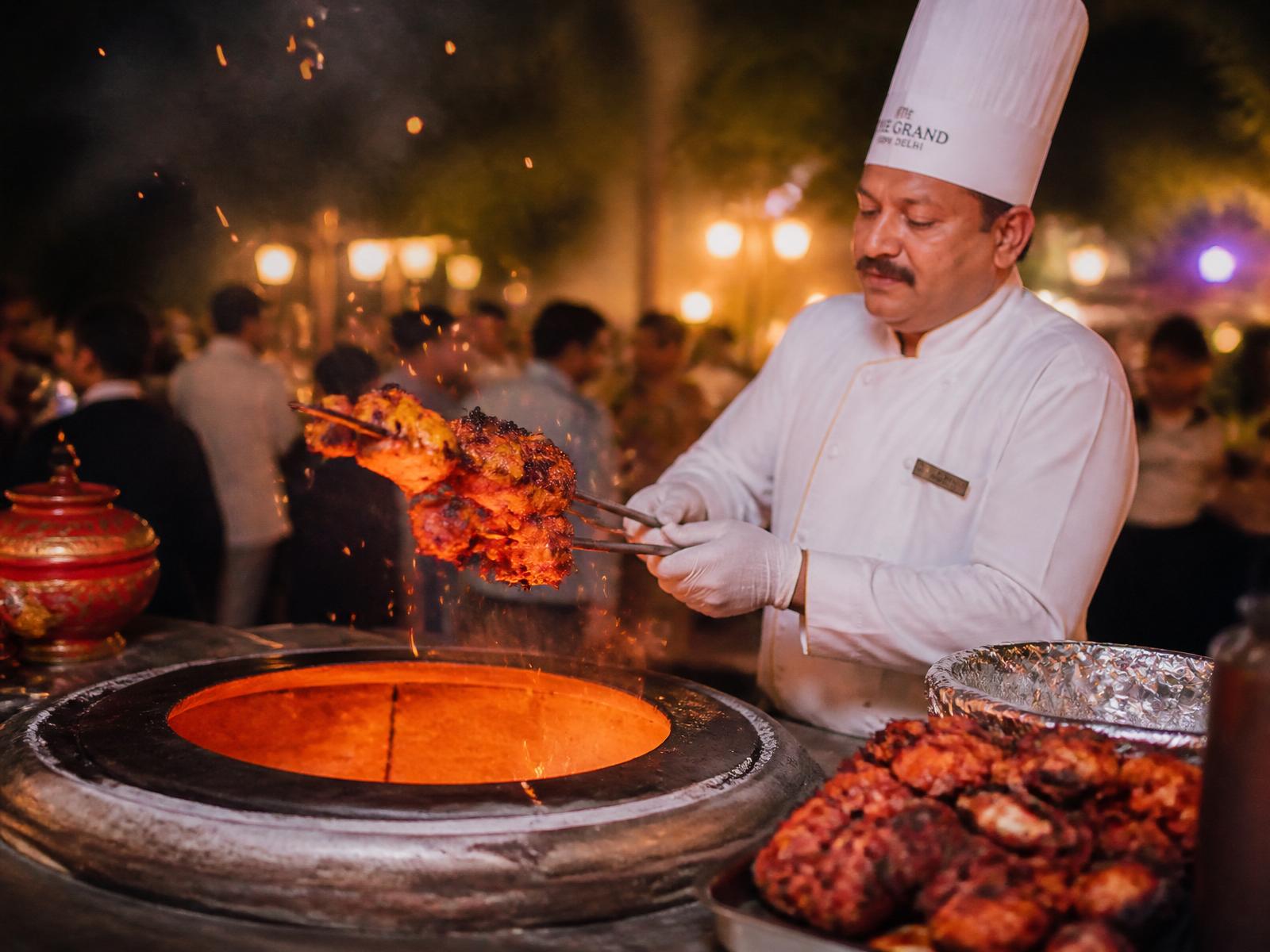 MAA chef grilling tandoori skewers at an outdoor catering event